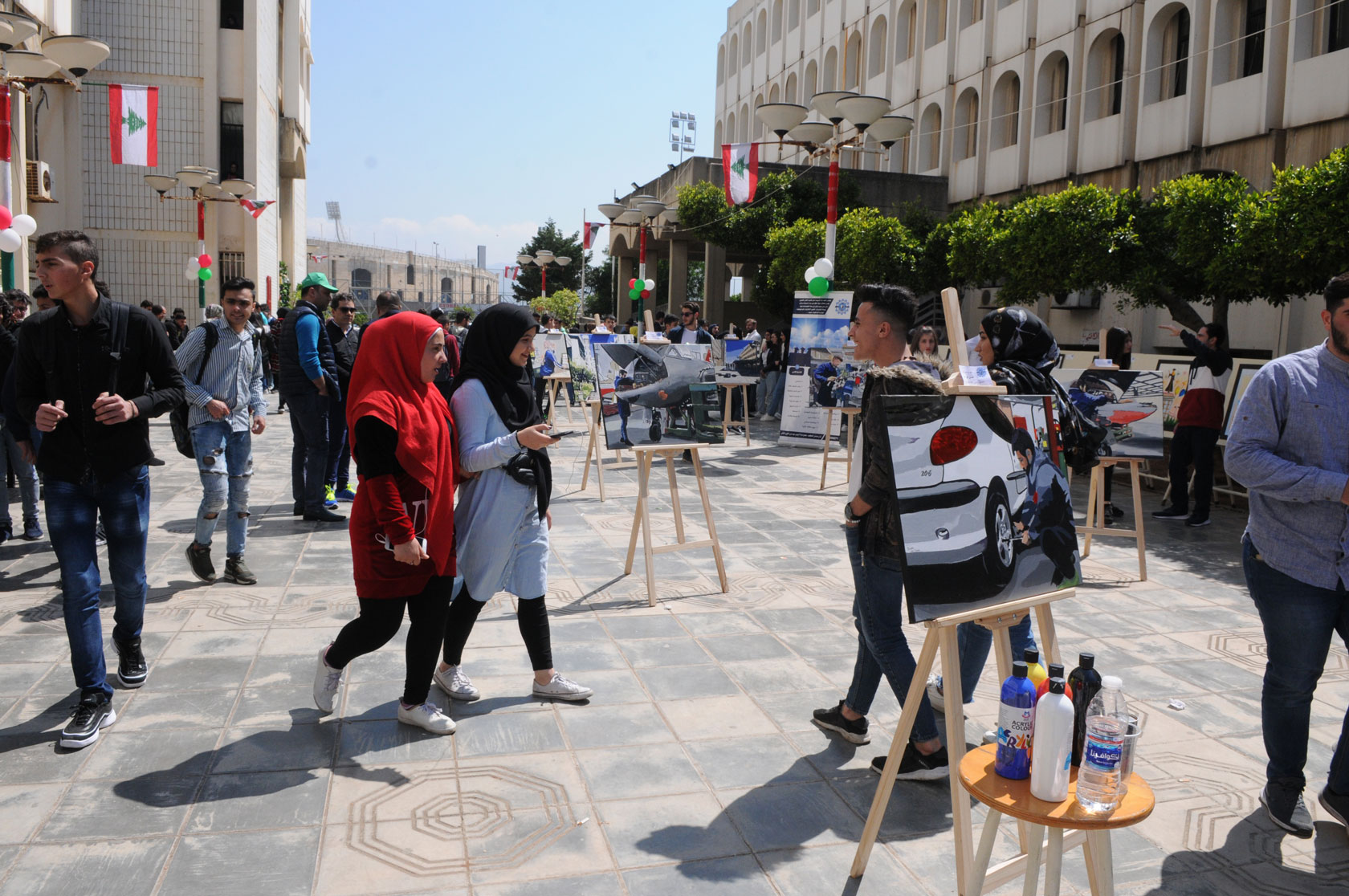 طلاب يتجولون بين لوحات ومشاريع المعرض في ساحة المعهد